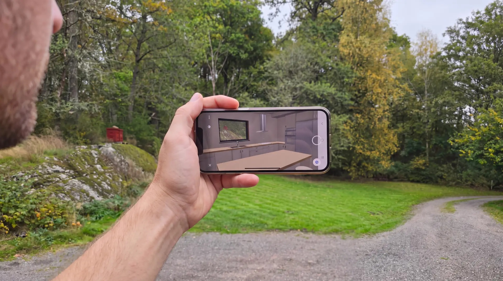 A house placed on its plot in augmented reality, viewed through a mobile phone